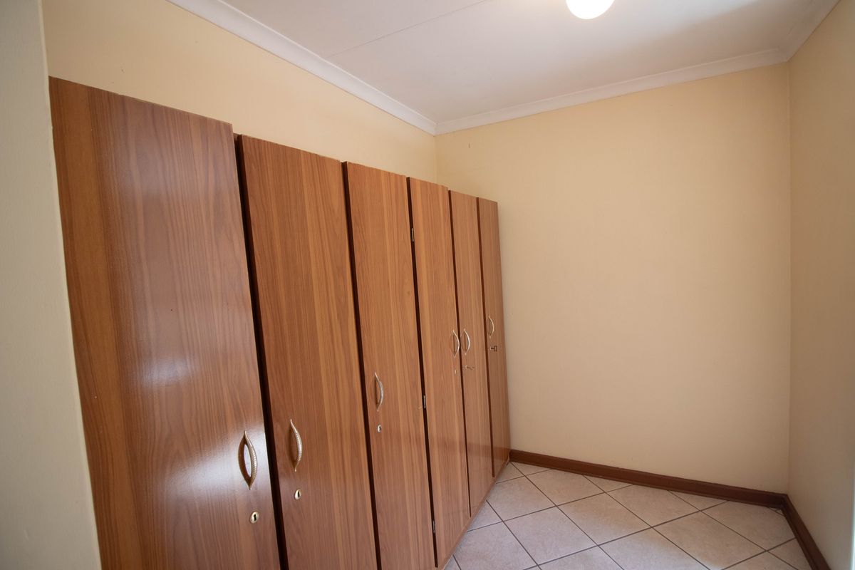 A bedroom featuring built-in wooden cupboards and tiled flooring.