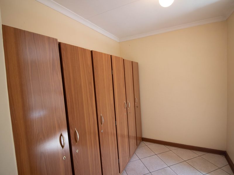 A bedroom featuring built-in wooden cupboards and tiled flooring.