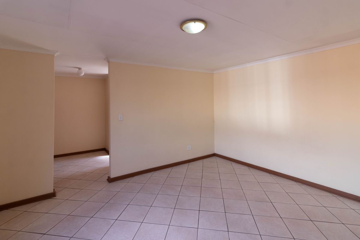 A vacant living area featuring neutral wall paint, tiled flooring, and a simple ceiling-mounted light fixture, offering a clean and versatile space.