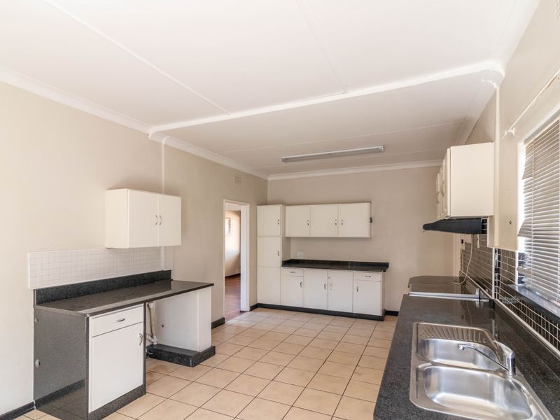 A functional kitchen featuring dark granite countertops, white cabinetry, a double stainless steel sink, and tiled flooring.