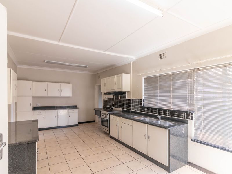 A functional kitchen featuring granite countertops, tiled splashbacks, built-in cabinetry, and a freestanding stove, offering a clean and practical workspace.