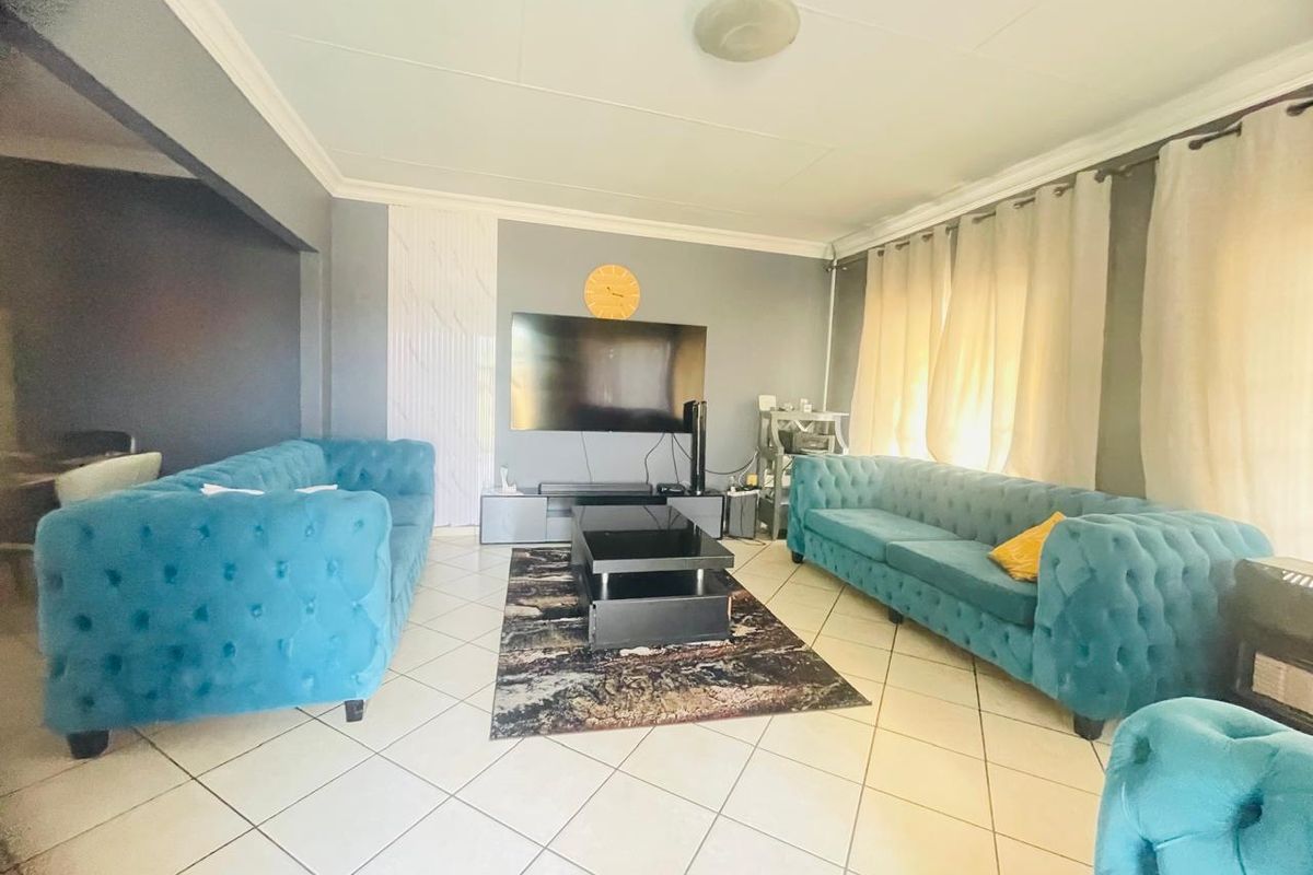 A spacious living room featuring tiled flooring, crown molding, and a neutral wall finish, providing a comfortable area for relaxation and entertainment.
