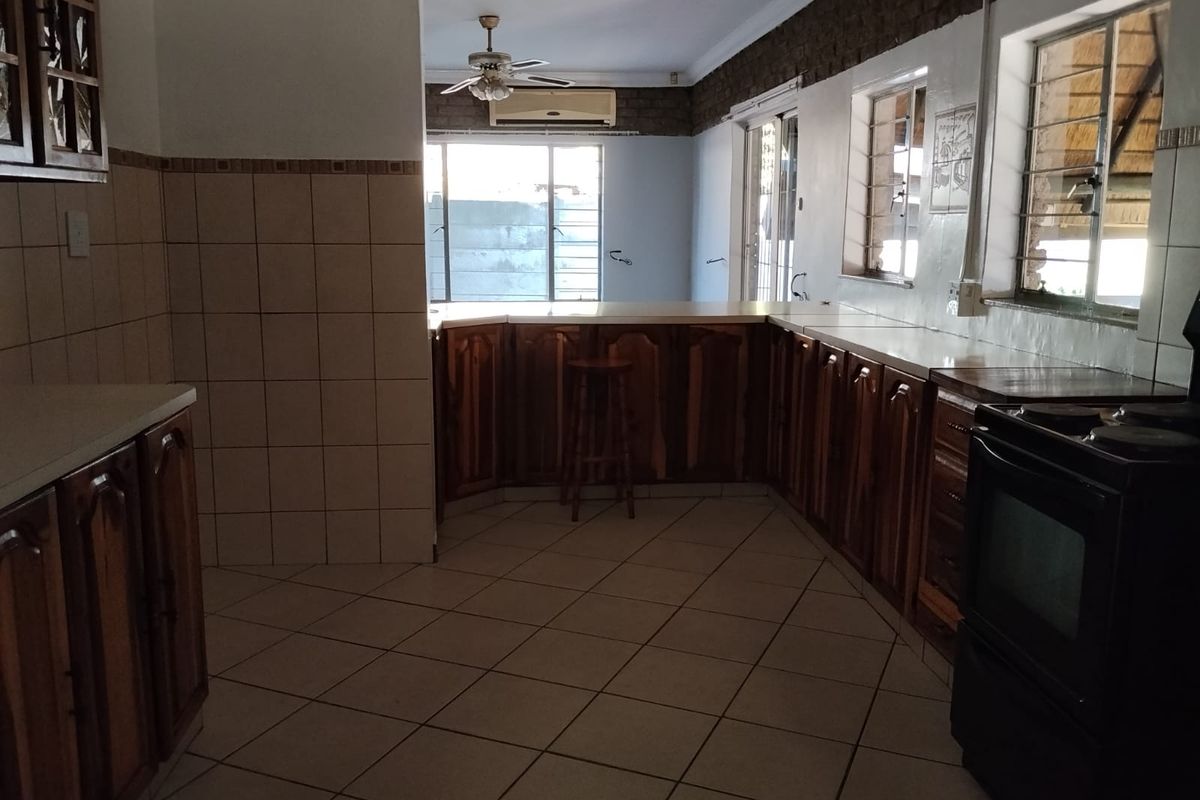 Spacious kitchen featuring wooden cabinetry, tiled flooring, and a breakfast bar, offering a functional layout with potential for modern updates.