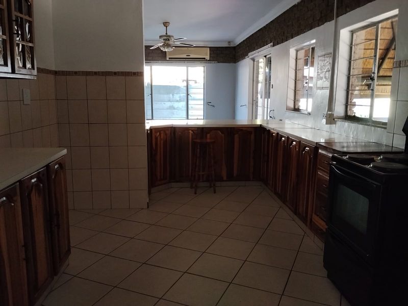 Spacious kitchen featuring wooden cabinetry, tiled flooring, and a breakfast bar, offering a functional layout with potential for modern updates.