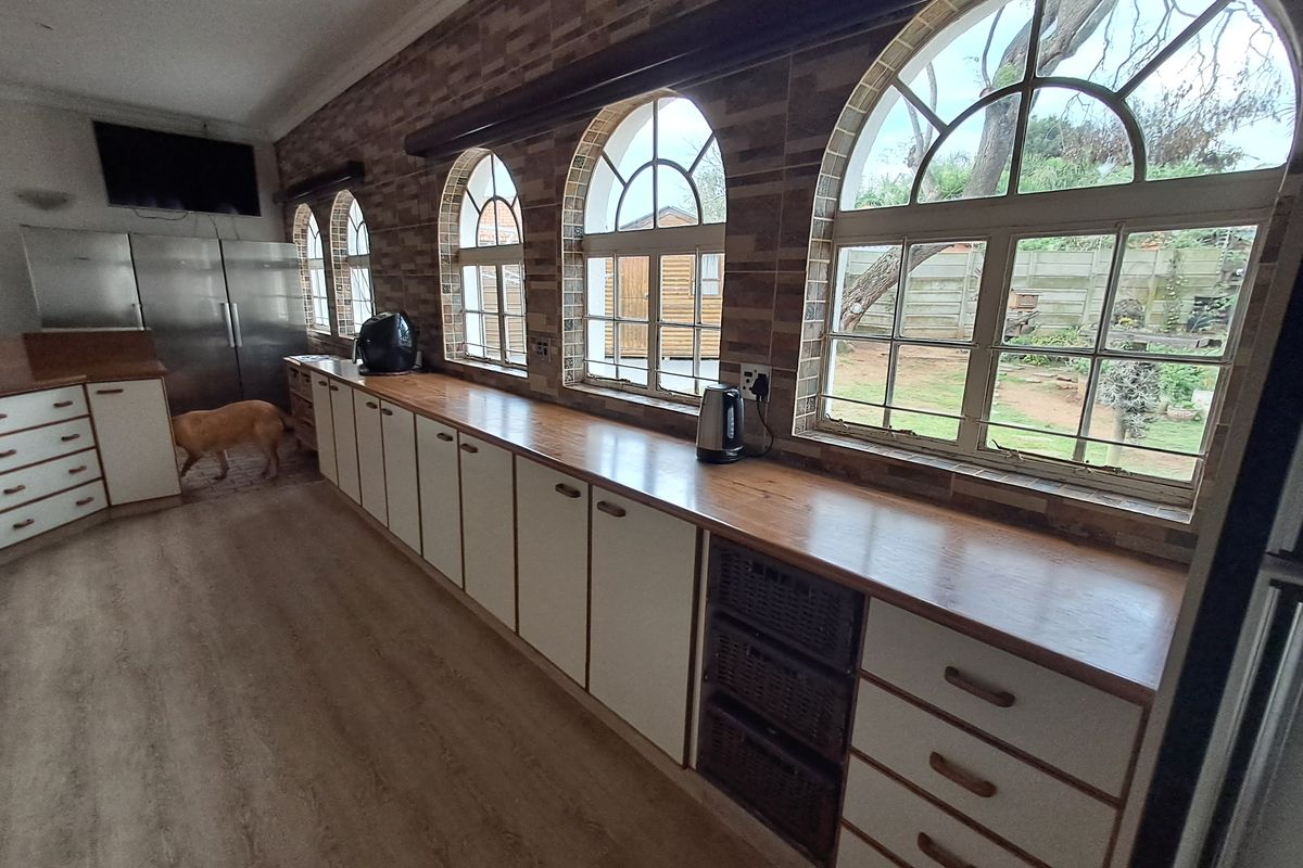 Spacious kitchen featuring extensive built-in cabinetry, wooden countertops, and distinctive arched windows overlooking the garden.