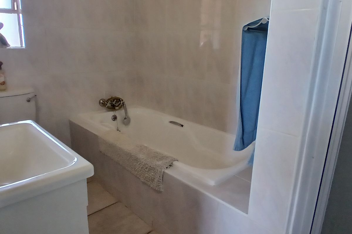 A functional bathroom featuring a built-in bathtub, a vanity basin, and tiled wall finishes.