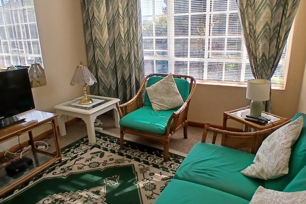 A cozy living room featuring large windows with horizontal blinds, providing ample natural light and a view of the exterior.