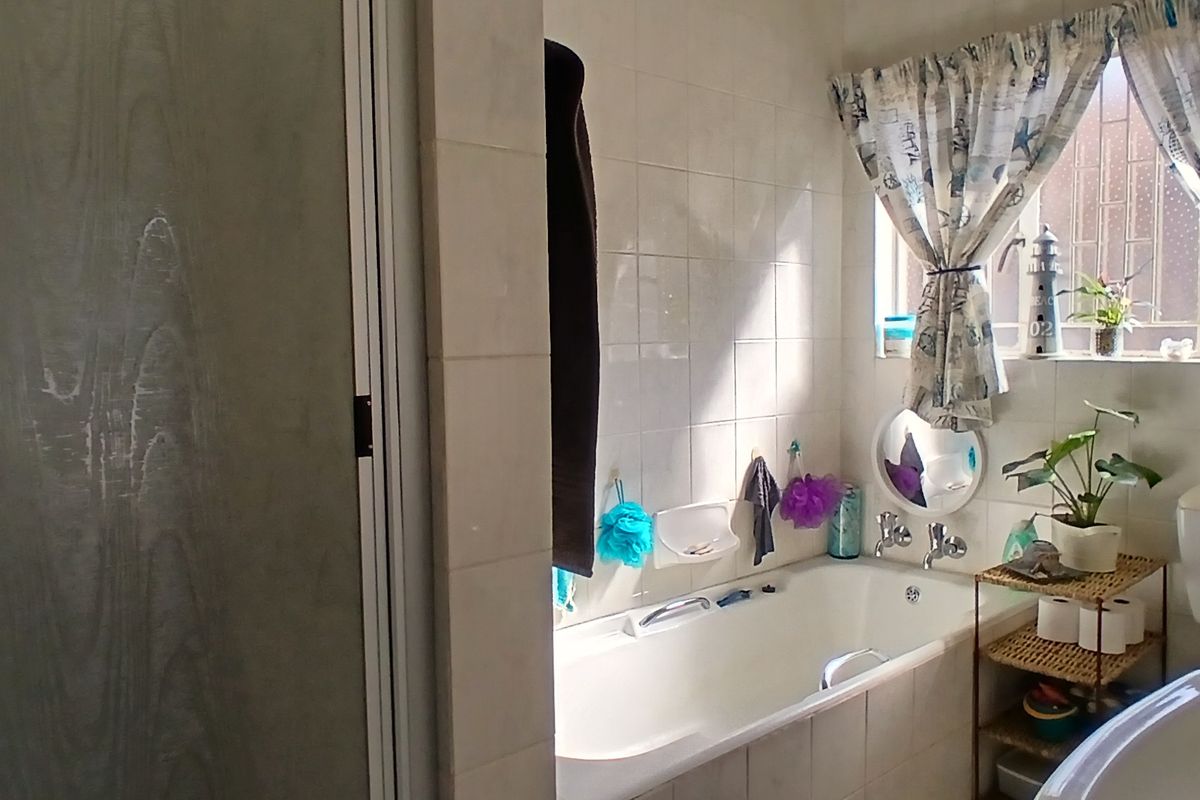 A functional bathroom featuring a built-in bathtub, tiled walls, and a window with security bars, providing a practical space for daily use.