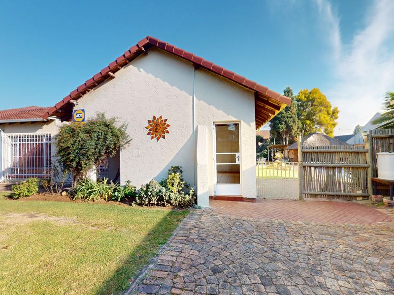 Front exterior view of the house featuring a paved driveway, tiled roof, and secure gated access to the side yard.