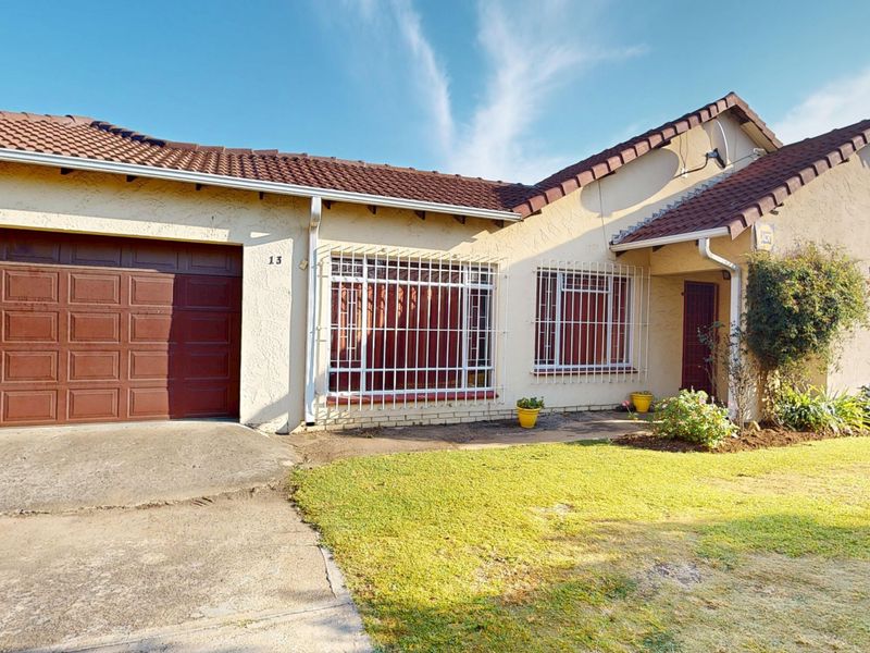 Front elevation of a single-story house featuring a tiled roof, integrated garage, and security bars on windows with a concrete driveway and lawn.