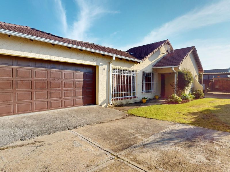 Front exterior view of the house featuring a double garage, concrete driveway, and security bars on the windows.