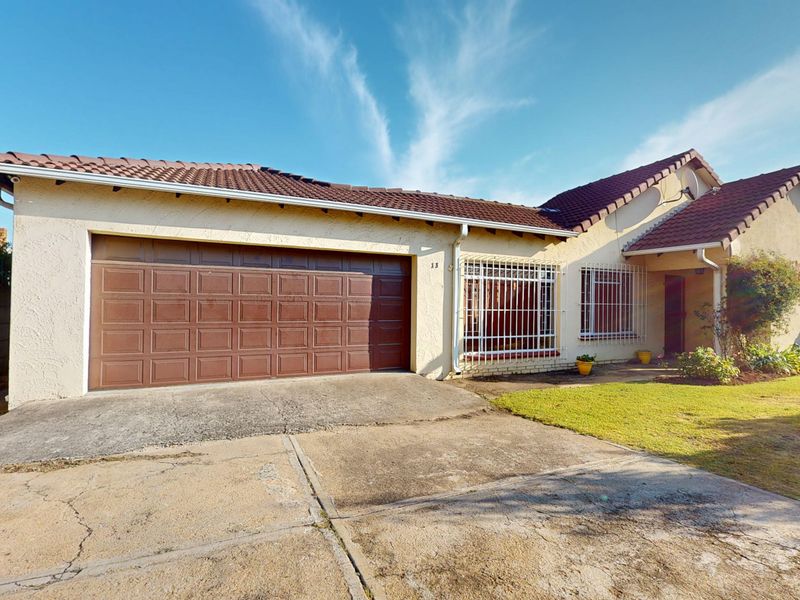 Front elevation of a single-story house featuring a double garage, tiled roof, and security bars on windows with a concrete driveway.