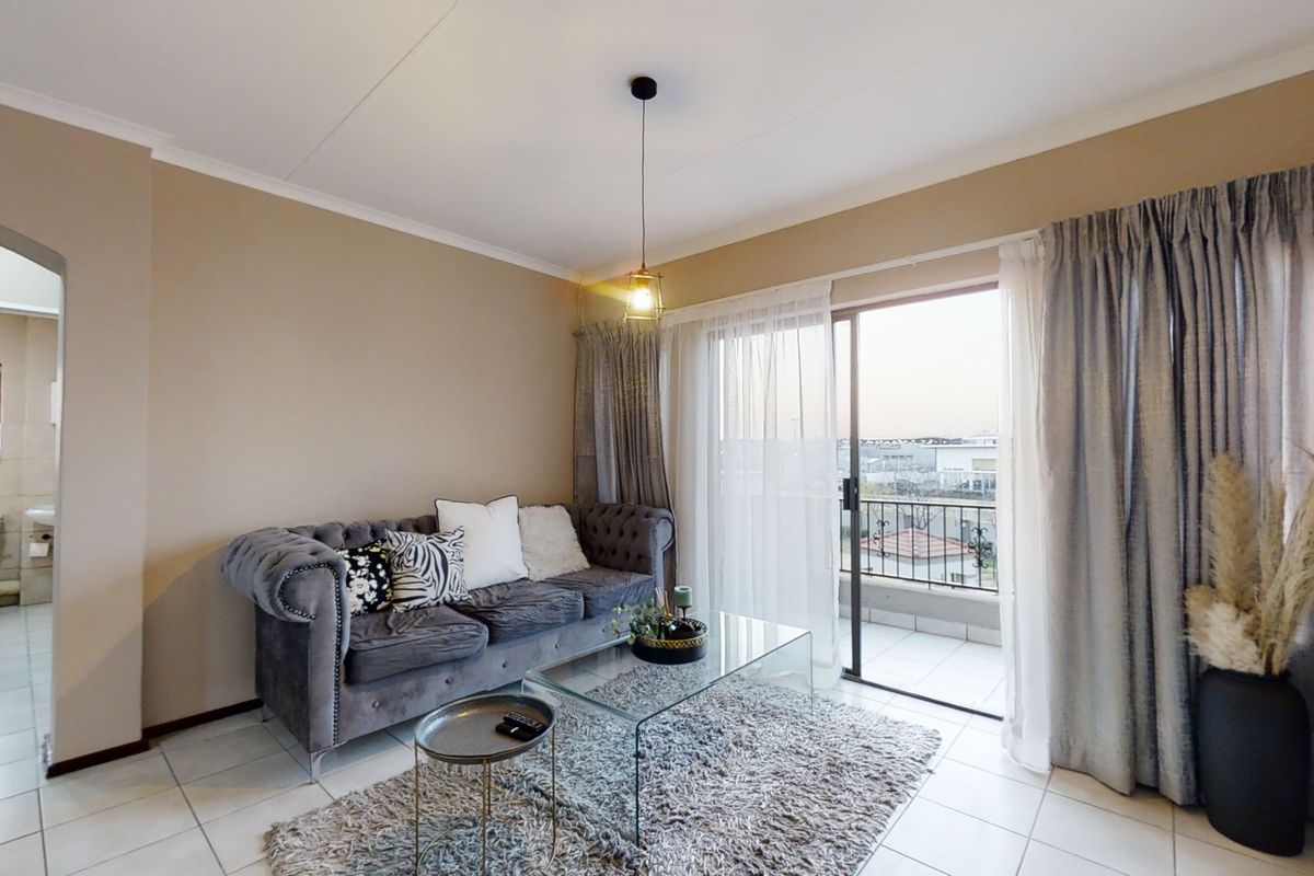 A living room featuring tiled flooring, a pendant light fixture, and a sliding glass door providing access to a balcony.