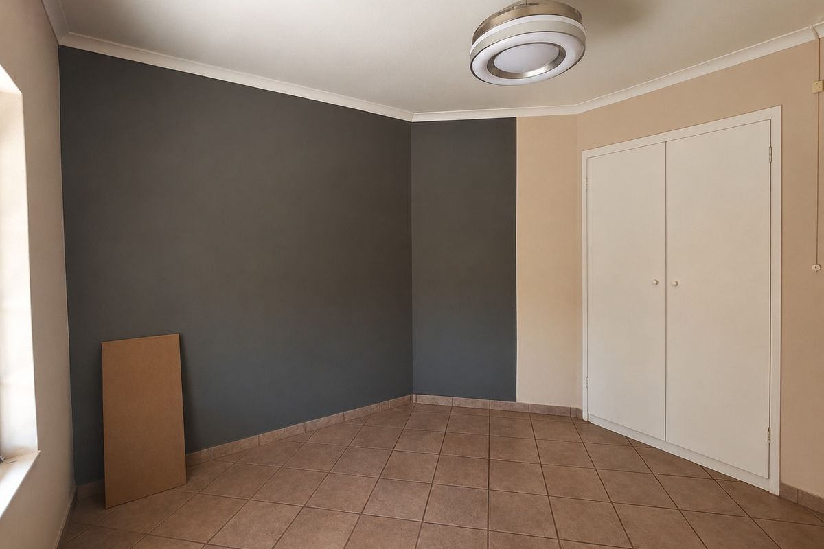 An empty bedroom featuring tiled flooring, built-in cupboards, and a modern ceiling fan with integrated lighting.