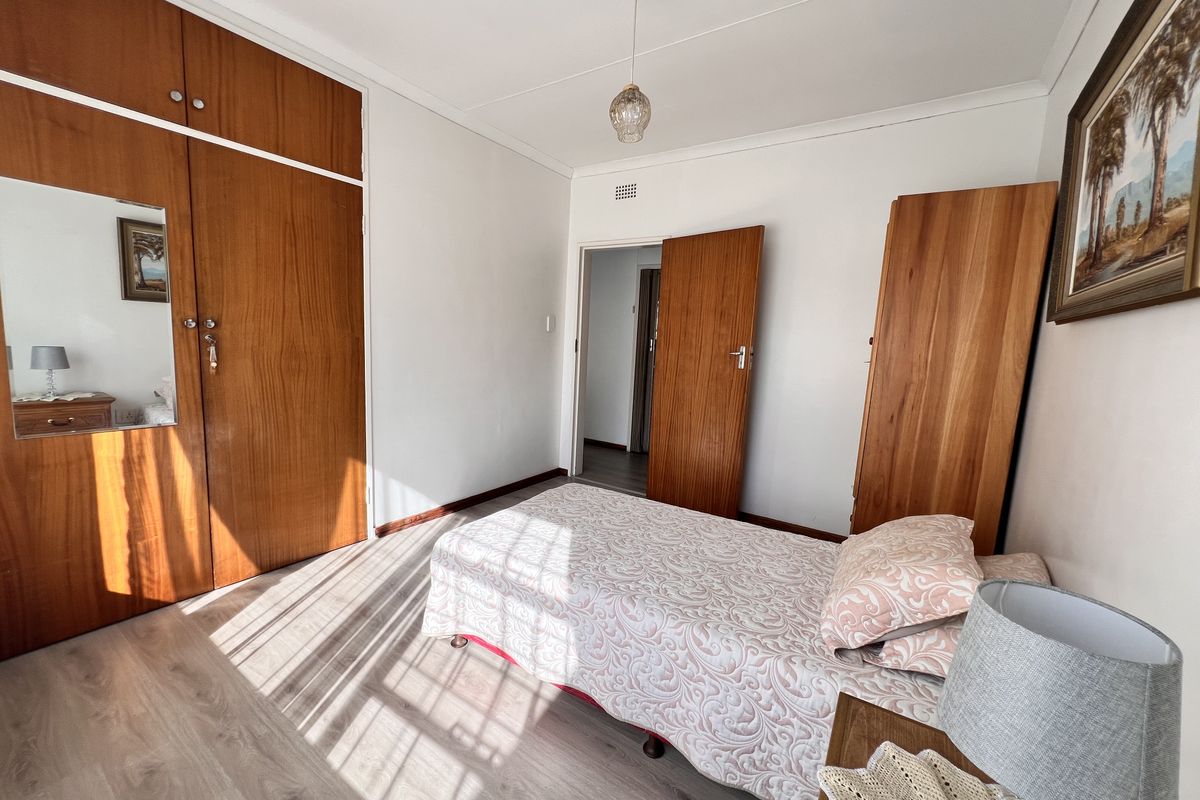 A bedroom featuring built-in wooden cupboards, laminate flooring, and a coved ceiling, offering a functional and well-maintained living space.