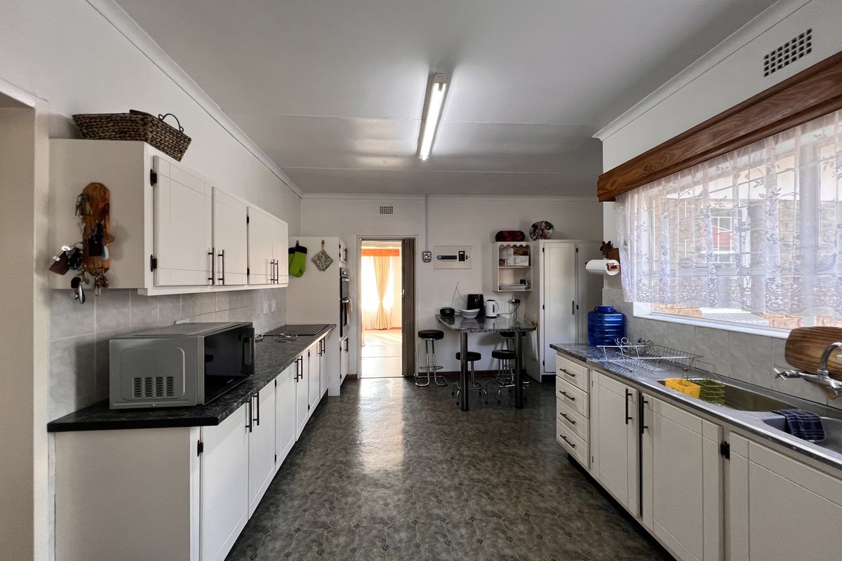 A functional kitchen featuring white cabinetry, laminate countertops, a stainless steel sink, and a built-in oven with a breakfast nook area.