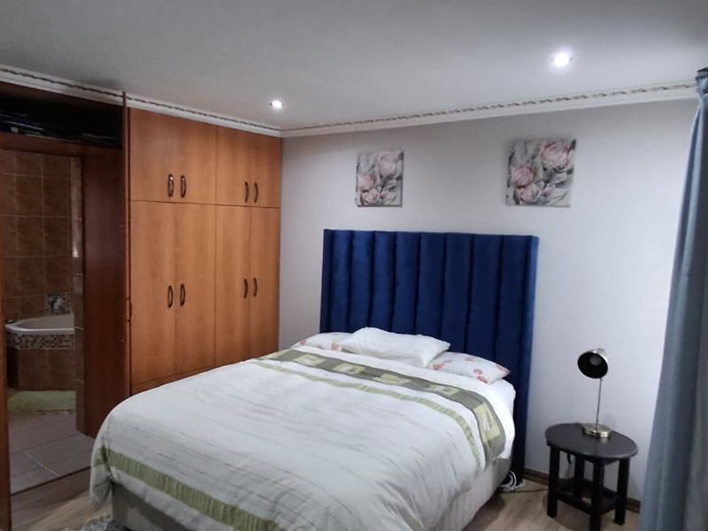 A well-maintained bedroom featuring extensive built-in wooden cabinetry, recessed ceiling lighting, and direct access to an en-suite bathroom.