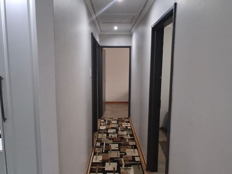 A clean, well-lit hallway providing access to multiple rooms, featuring neutral walls and recessed ceiling lighting.