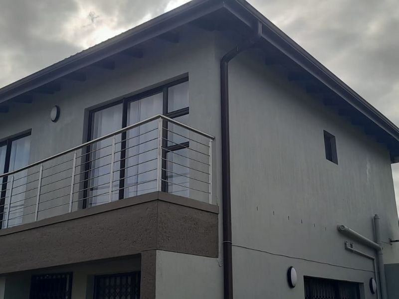 A view of the rear exterior facade featuring a balcony with a stainless steel balustrade and modern sliding doors.
