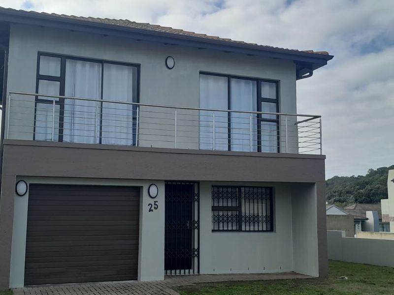 A two-story residential property featuring a ground-level garage, a security-gated entrance, and an upper-level balcony with stainless steel balustrades.