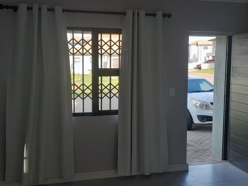 Entrance area featuring tiled flooring, a timber door, and a window with a security gate, providing direct access to the exterior driveway.