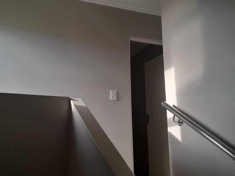A simple hallway or stairwell area featuring a metal handrail and neutral wall finishes.