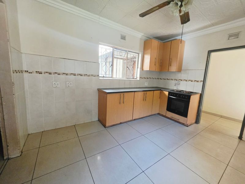 A functional kitchen featuring built-in cabinetry, tiled splashbacks, tiled flooring, and a built-in oven with hob, offering a clean and practical workspace.