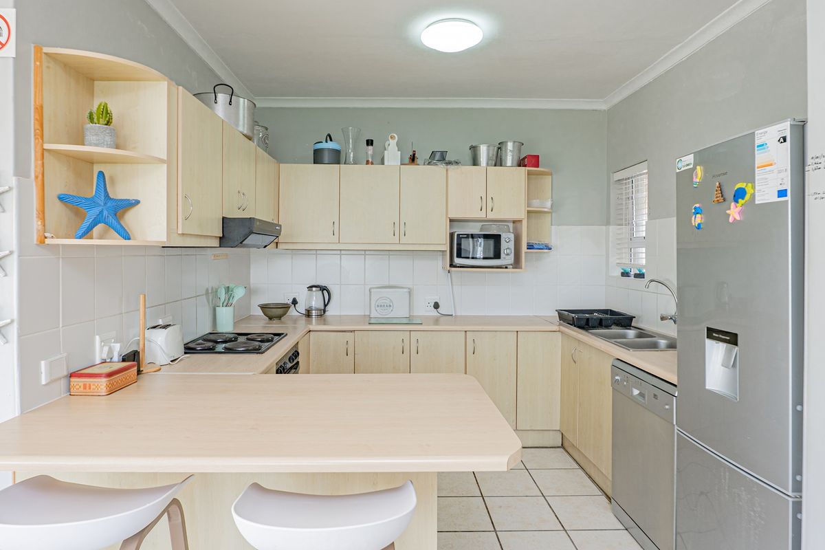 A functional kitchen featuring light wood-tone cabinetry, laminate countertops, a breakfast bar, and tiled flooring, offering a practical layout for daily meal preparation.