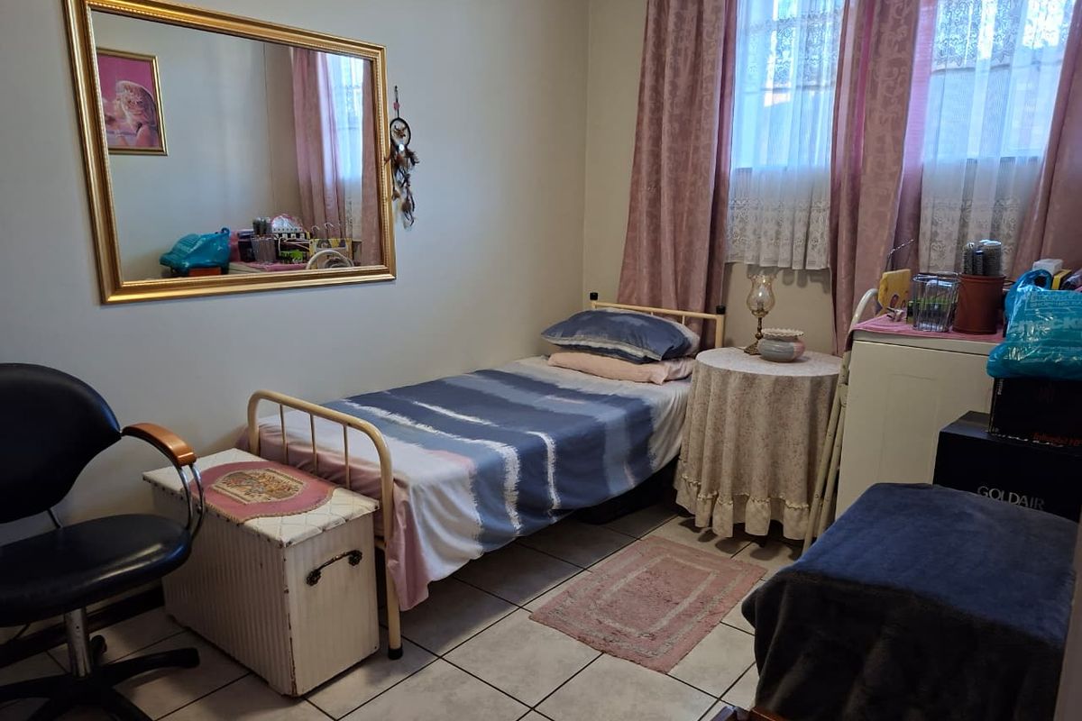 A bedroom featuring tiled flooring and a window with curtains, providing a functional living space.
