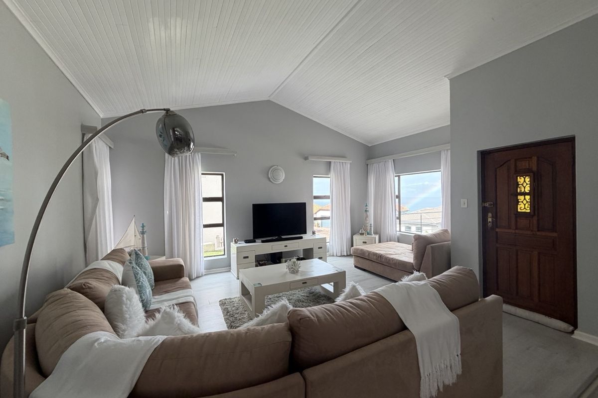 Spacious living room featuring a vaulted tongue and groove ceiling, tiled flooring, and a classic timber entrance door with decorative glass detailing.