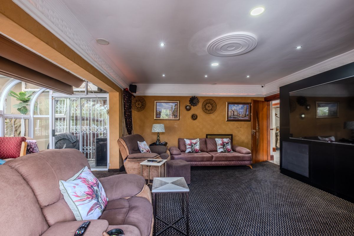 Spacious living room featuring recessed ceiling lighting, decorative ceiling rose, and large sliding glass doors providing access to the patio area.