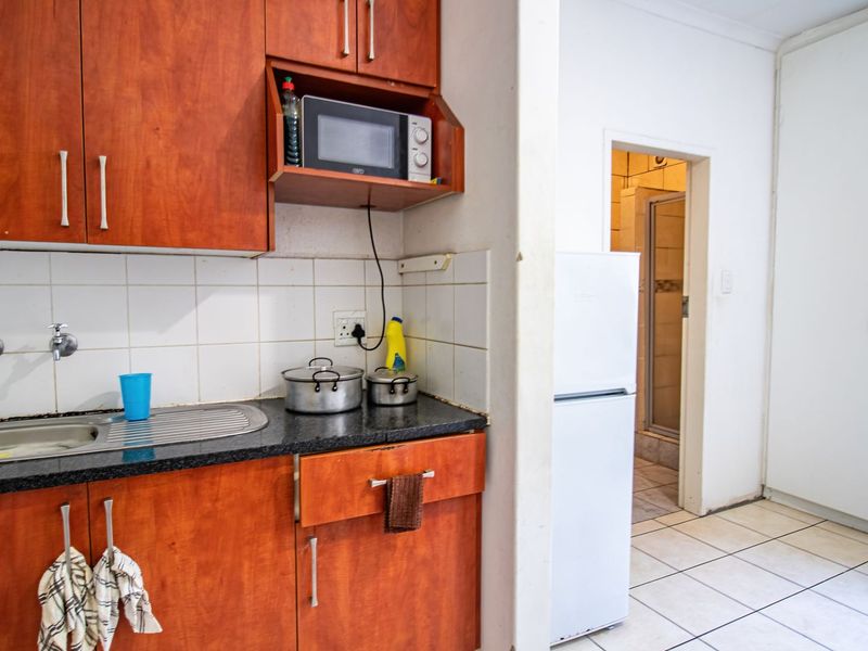 Compact kitchen featuring laminate cabinetry, granite countertops, and a tiled backsplash, with direct access to an adjacent bathroom area.