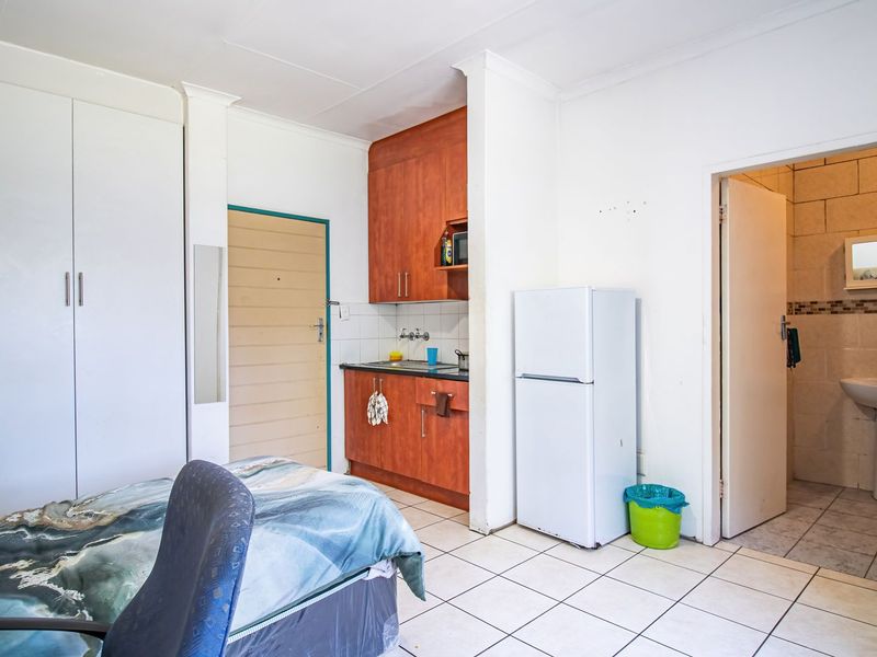 Open-plan studio apartment featuring tiled flooring, built-in storage cupboards, a compact kitchenette, and direct access to an en-suite bathroom.