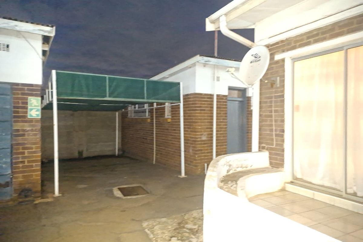 Exterior view of the property featuring a covered carport, brick facade, and a small patio area with sliding door access.