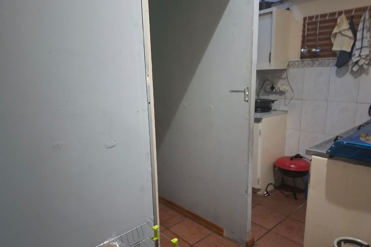A view into a compact kitchen area featuring tiled flooring, built-in cabinetry, and tiled splashbacks.
