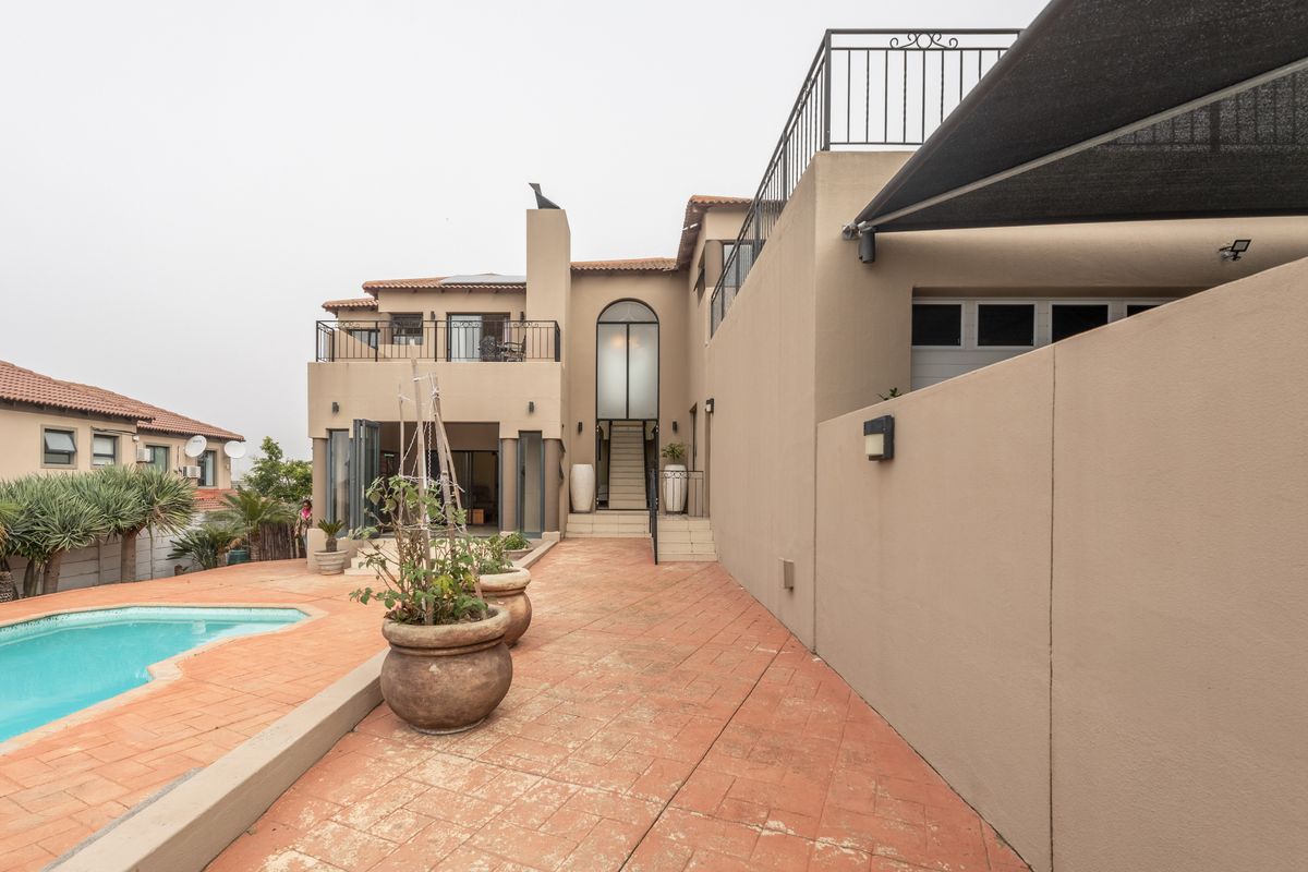 Rear view of the property featuring a swimming pool, paved patio area, and multi-level terrace with metal railings.
