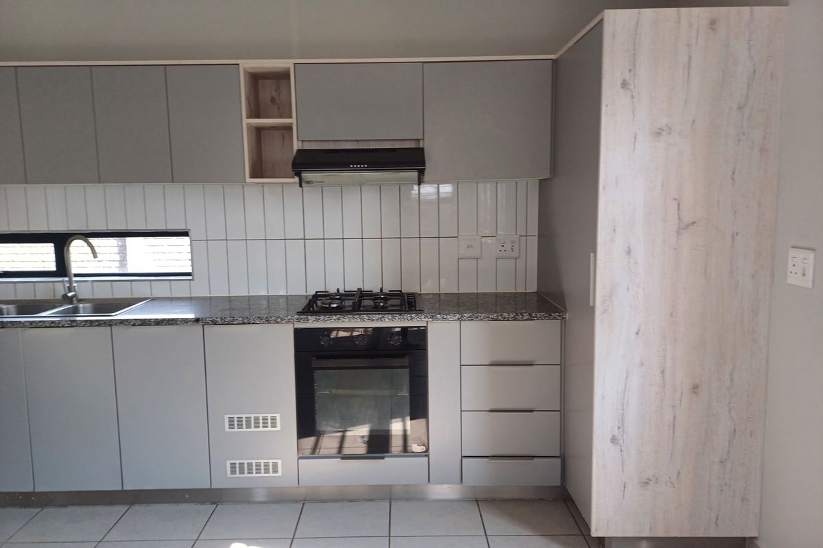 Modern kitchen featuring grey cabinetry, granite countertops, a built-in oven, gas hob, extractor fan, and tiled backsplash.