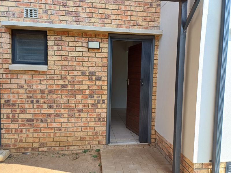 Exterior view of the apartment entrance featuring face brick facade, a secure door, and a small paved entryway.