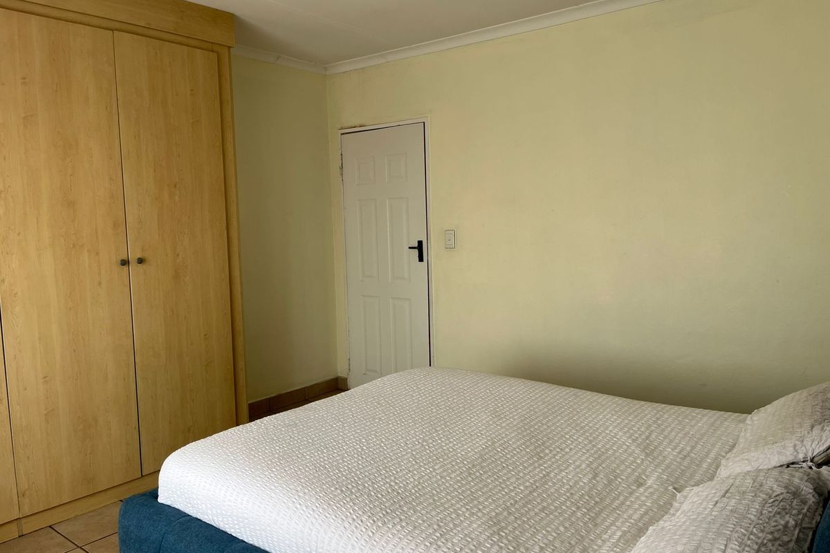 A bedroom featuring tiled flooring, a built-in wooden wardrobe, and a coved ceiling.