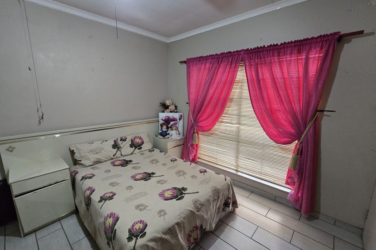 A bedroom featuring tiled flooring, a ceiling fan, and a built-in headboard with integrated side tables.