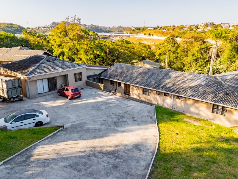 Aerial view of the property showing the main house structure, extensive concrete driveway, and surrounding landscaped grounds.