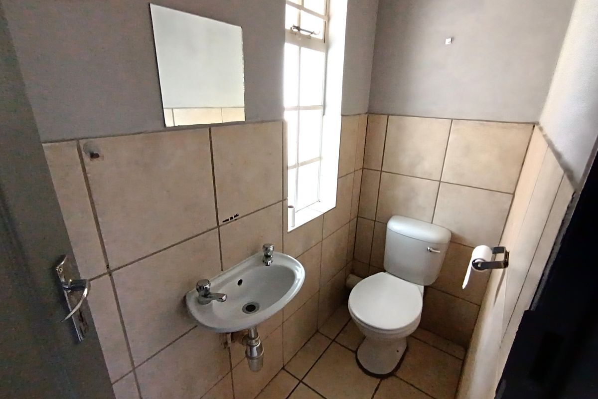 A compact guest bathroom featuring a wall-mounted basin, a standard toilet, and tiled walls and flooring.
