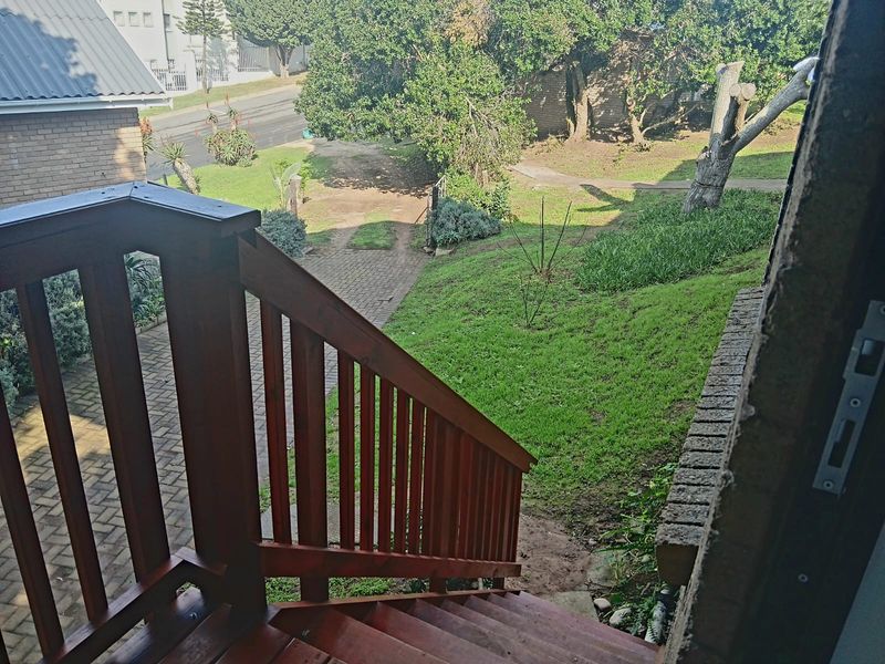 An elevated timber staircase leading down to a paved walkway and garden area, providing outdoor access from the cottage.
