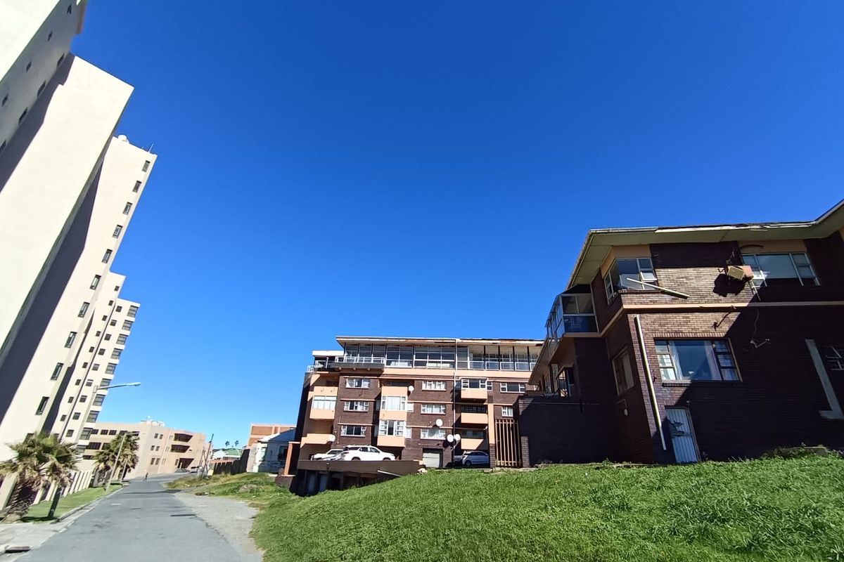Exterior view of a multi-story residential building complex featuring brick facades, balconies, and surrounding landscaped grounds.