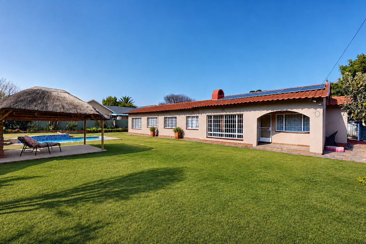 Spacious rear garden featuring a swimming pool, a thatched lapa with a built-in fireplace, and a well-maintained lawn area with solar panels on the roof.