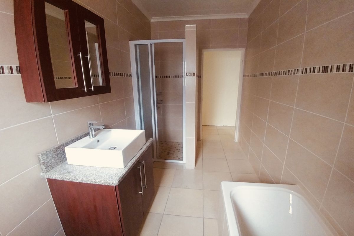 A functional bathroom featuring a vanity with vessel sink, a separate shower enclosure, and a bathtub with full-height wall tiling.