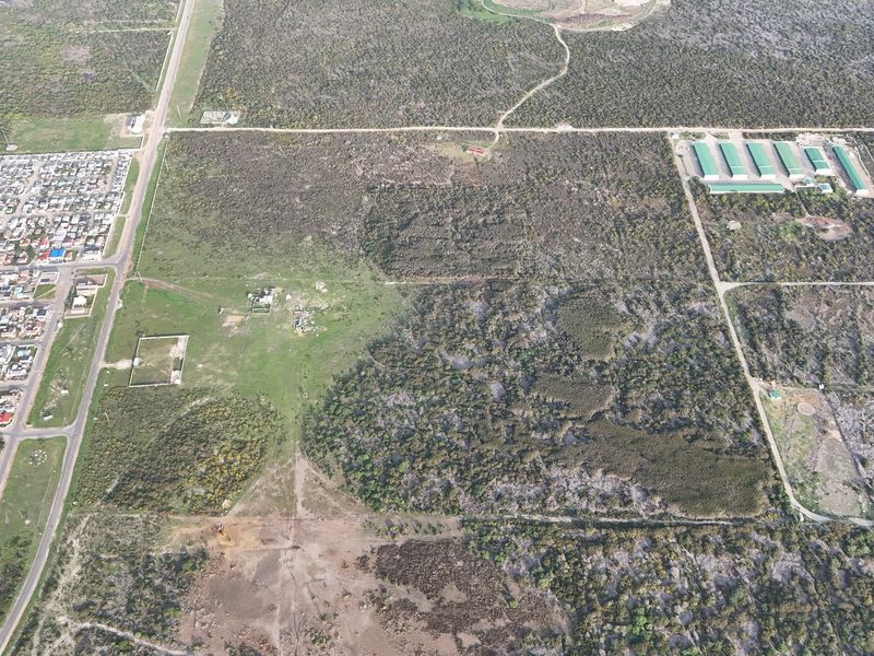 An aerial view of a large, undeveloped residential land parcel featuring natural vegetation and surrounding road access.