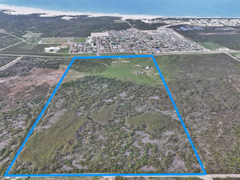 Aerial view of a large, undeveloped residential plot featuring native coastal vegetation, situated near the coastline and local residential area.
