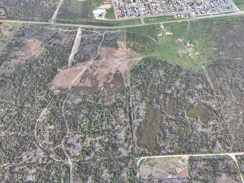 An aerial view of a large, undeveloped residential land parcel featuring natural vegetation and existing dirt access tracks.
