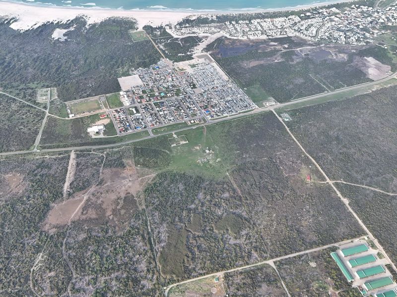 An aerial view of the residential area and surrounding coastal landscape, showcasing the property's location and proximity to the beach.